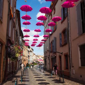 Jakobsweg Moissac rosa Oktober Regenschirme Einkaufsstraße sonnig blauer Himmel
