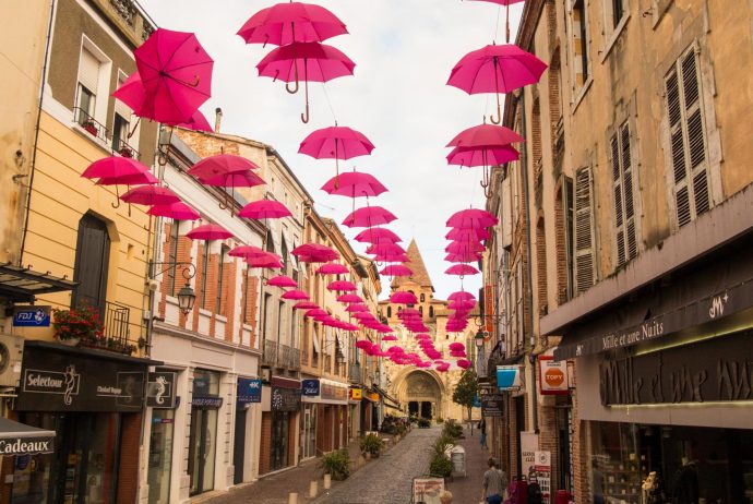 Jakobsweg Moissac rosa Oktober Regenschirme entlang der Straße mit Kirche