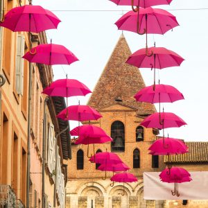 Jakobsweg Moissac rosa Oktober Regenschirme vor Kirchturm